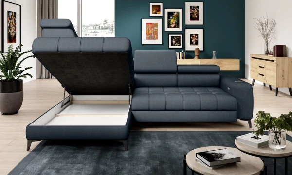 Canapé d'angle gris foncé avec un compartiment de rangement ouvert, situé dans un salon moderne. Mur bleu canard décoré de cadres artistiques, parquet clair, buffet en bois, table basse ronde avec plateau clair et plantes en pot pour une touche naturelle.