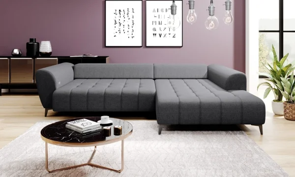 Canapé d'angle gris moderne au design minimaliste, installé dans un salon contemporain. Mur violet orné de tableaux graphiques en noir et blanc, parquet clair, table basse en marbre noir avec cadre doré, tapis beige texturé, et plantes vertes en pot pour une ambiance chaleureuse.