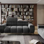 Canapé 3 places gris foncé avec appuie-têtes ajustables, dans un salon élégant doté d'une bibliothèque en bois, d'un tapis moderne et de tables d'appoint noires.