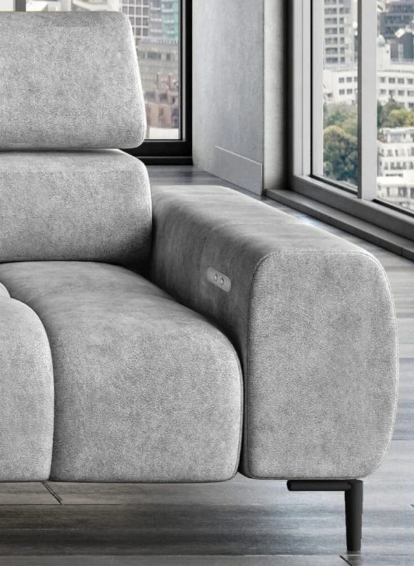 Accoudoir du canapé gris clair avec boutons intégrés, dans un espace moderne avec vue panoramique sur la ville.