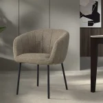 Chaise Séville en tissu beige avec pieds en métal noir, intégrée dans un espace moderne et élégant, entourée de décorations naturelles et contemporaines.