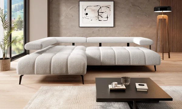 Canapé blanc moderne en tissu bouclé, accompagné de coussins moelleux. Installé dans un salon lumineux avec des finitions en bois et une décoration minimaliste, il reflète une ambiance chaleureuse et contemporaine. Une table basse en bois foncé et des éléments de lumière naturelle accentuent le design épuré.